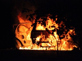 Firefighters work to put out a blaze in a vehicle linked to a double targeted shooting in Surrey Friday night.