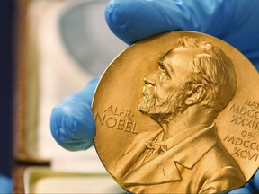 In this file photo dated Friday, April 17, 2015, a national library employee shows the gold Nobel Prize medal