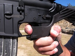 Shooting instructor Frankie McRae illustrates the grip on an AR-15 rifle fitted with a "bump stock" at his 37 PSR Gun Club in Bunnlevel, N.C., on Wednesday, Oct. 4, 2017. The stock uses the recoil of the semiautomatic rifle to let the finger "bump" the trigger, making it different from a fully automatic machine gun, which are illegal for most civilians to own. (AP Photo/Allen G. Breed)