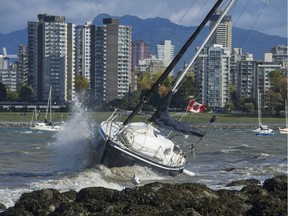 Waves and heavy wind pound an unmoored sailboat that washed ashore at Kits Point in Vancouver, on Oct. 17, 2017.