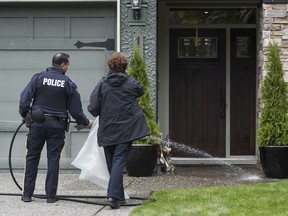 RCMP officers clean the blood from the front entry way of a house on the 14300-block of Crescent Road in Surrey, following an early morning shooting that left a man died and a woman in serious condition, October, 23, 2017.