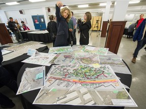 People examine concept drawings after director of transportation Lon LaClaire led an unveiling of preliminary proposed ideas for the Arbutus Greenway at Point Grey Secondary in Vancouver on Sunday.