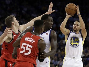 Golden State Warriors' Stephen Curry, right, shoots against the Raptors' Jakob Poeltl, left, during the second half of their game Wednesday night in Oakland, Calif. The Warriors won 117-112.