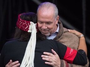 B.C. Premier John Horgan hugs a First Nations woman after being wrapped in a Musqueam blanket during a ceremony after the Walk for Reconciliation in Vancouver, B.C., on Sunday September 24, 2017. The two kilometre walk was held to promote positive relations between Indigenous and non-Indigenous people in Canada.