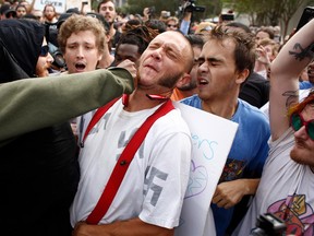 A man wearing a shirt with swastikas on it is punched by an unidentified member of the crowd near the site of a planned speech by white nationalist Richard Spencer at the University of Florida campus on Oct. 19, 2017 in Gainesville, Florida.