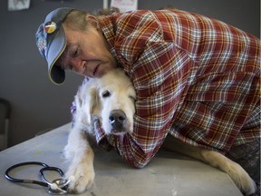 Mark Matthews comforts his dog Bounder, who has lymphocytic leukemia, while being examined by Dr. Ben Weinberger at a free animal health care clinic in the Downtown Eastside of Vancouver, B.C., on Thursday October 26, 2017.