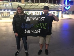 Tom Biro and Heather Satterberg display the Anti-Racism, Anti-Facsim, Always Seattle banner which got them ejected from BC Place on Sunday night. Biro and Satterberg are co-presidents of Emerald City Supporters, a Seattle Sounders fan group. [PNG Merlin Archive] Tom Biro, PNG