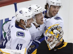 Brock Boeser of the Vancouver Canucks, centre, celebrates his goal against the Pittsburgh Penguins on Wednesday with teammates Sven Baertschi, left, and Ben Hutton. Pittsburgh goalie Matt Murray looks on.