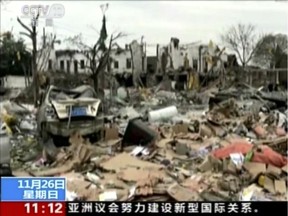 In this image from video run by China's CCTV, firefighters and people, right, walk near damaged buildings and vehicles following an explosion in Ningbo in east China's Zhejiang province, Sunday, Nov. 26, 2017. A factory explosion in a port south of Shanghai knocked down buildings and left streets littered with damaged cars and debris, news reports said.(CCTV via AP Video)