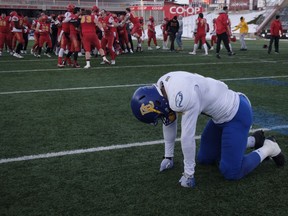University of British Columbia Thunderbirds' Will Maxwell, foreground reacts as the University of Calgary Dinos' celebrate their victory following the USports Hardy Cup football game in Calgary, Saturday.
