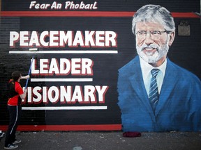 FILE - In this Friday, May, 2 2014 file photo, a man adds the finishing touch to a newly painted mural of Gerry Adams on the Falls Road, West Belfast, Northern Ireland. Gerry Adams has announced that he plans to step down as leader of Sinn Fein next year after heading the party for over 30 years. Adams said in a speech at the party's annual conference in Dublin on Saturday, Nov. 18, 2017 that he will not stand for the next Irish parliamentary election.