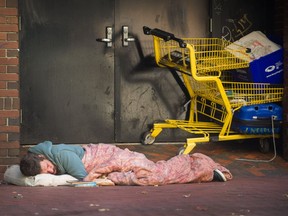 A homeless man sleeps on the sidewalk in Vancouver.