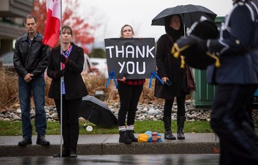 A woman holds a sign while the funeral procession carrying the body of Abbotsford Police Const. John Davidson, who was killed in the line of duty Nov. 6, makes its way to a memorial service in Abbotsford on Sunday, Nov. 19, 2017.