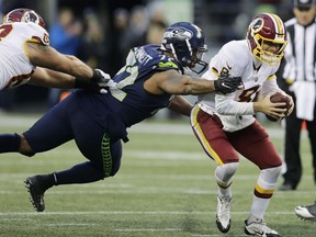 Washington Redskins quarterback Kirk Cousins, right, scrambles away from a tackle attempt by Seattle Seahawks defensive end Michael Bennett, left, in the second half of an NFL football game, Sunday, Nov. 5, 2017, in Seattle.