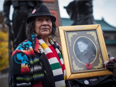 Viviane Sandy, of the Secwepemc (Shuswap) First Nation, from Williams Lake, B.C., holds a photo of her great-uncle George Gilbert, who served in the Second World War, while attending a Remembrance Day ceremony honouring the sacrifices of the early Chinese pioneers and Chinese-Canadian military veterans, in Chinatown in Vancouver, B.C., on Saturday November 11, 2017.