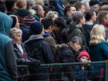 A young boy and an elderly woman listen while standing in the crowd during a Remembrance Day ceremony in Vancouver, B.C., on Saturday November 11, 2017.