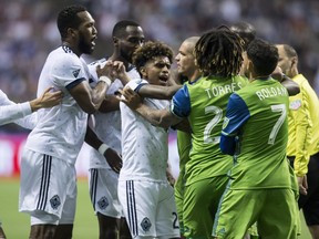 Vancouver Whitecaps' Kendall Waston, left, and Yordy Reyna, centre left, get into a scuffle with Seattle Sounders' Osvaldo Alonso, centre right, and Roman Torres during the second half of an MLS playoff soccer game in Vancouver, B.C., on Sunday.