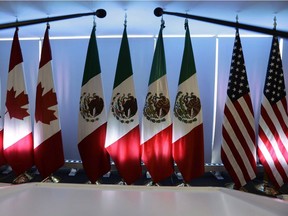 National flags representing Canada, Mexico, and the U.S. are lit by stage lights at the North American Free Trade Agreement renegotiations.