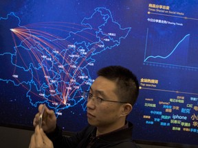 A visitor to the command center for Chinese e-commerce giant JD.com stands near a digital map showing the flow of deliveries across the country in Beijing, China, Saturday, Nov. 11, 2017. Chinese consumers are spending billions of dollars shopping online for anything from diapers to diamonds on "Singles Day," a day of promotions that has grown into the world's biggest e-commerce event. (AP Photo/Ng Han Guan)