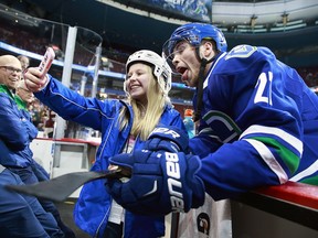 Ben Hutton of the Vancouver Canucks takes a photo with a fan before his NHL game against the Calgary Flames at Rogers Arena in January. The defenceman returns to the lineup tonight against St. Louis after being a healthy scratch the last two games.