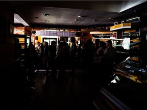 People queue inside a bakery's and fast food shop, during a power cut in Caracas on December 18, 2017.  Vast sectors of Caracas and northern Venezuela were without electricity on Monday due to an electrical fault, affecting vital services such as the metro in the capital, authorities said.