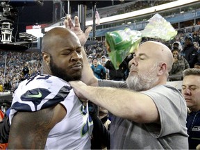 A Seattle Seahawks staff member tries to remove Seahawks defensive tackle Quinton Jefferson, left, from the field as an object thrown from the stands hits them during the closing moments of an NFL football game against the Jacksonville Jaguars, Sunday, Dec. 10, 2017, in Jacksonville, Fla. Jacksonville won 30-24.