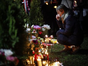 A woman wipes away tears in front of a memorial in support and memory of Aubrey Berry, 4, and her sister Chloe, 6, during a vigil held at Willows Beach in Oak Bay, B.C., on Saturday, December 30, 2017.