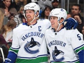 Derrick Pouliot (right) gets a hug from captain Henrik Sedin during an NHL game in Los Angeles against the Kings last month. Pouliot's passing has brought quicker zone exits for the Canucks.