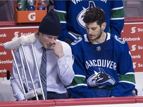 Vancouver Canucks right wing Brock Boeser is seen with crutches as he speaks to Vancouver Canucks center Nic Dowd following a loss to the Calgary Flames in Vancouver, Sunday. Boeser took a shot of his left foot early in the second period of Sunday's game against the Calgary Flames and did not return.