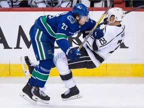 Vancouver Canucks' Ben Hutton, left, checks Los Angeles Kings' Dustin Brown during second period NHL hockey action in Vancouver on Saturday, December 30, 2017.