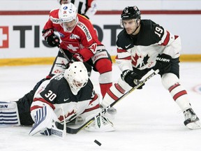 Switzerland's Reto Suri, centre, fight for the puck against Canada players goaltender Ben Scrivens, left, and Gilbert Brule during the 2017 Karjala Cup ice hockey match between Switzerland and Canada in the Tissot Arena in Biel, Switzerland, on Wednesday, Nov. 8, 2017. Russia's ban from the upcoming 2018 Pyeongchang Olympics could force Hockey Canada to drastically alter its course in assembling a men's national team.