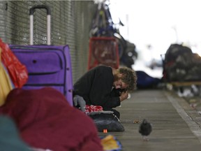 In this Oct. 12, 2017 photo, Dominic, who battles mental illness, sits on a sidewalk under the Smith Ave. Bridge in Everett, Wash., which is a constant gathering place for homeless people battling addiction and mental illness. Dominic has been identified as one of the top chronic and costliest users of emergency and other services in Everett, but despite the efforts of a specialized team of experts, he remains on the streets.