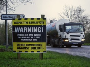 A truck drives past an "anti-Brexit" sign, set up by local activists, on a road on the outskirts of Middletown, Nothern Ireland, Britain, close to the border with Ireland, Thursday, Dec. 7, 2017. Britain and the bloc said Friday they had struck a deal ensuring that there will be no return to a "hard border" between Northern Ireland, which is part of the U.K., and EU member state Ireland after Brexit. That will not erase the fears of thousands who live or work across the currently invisible frontier.