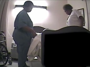 Screen grab of a video showing Wanda Nuckles walking into James Demosey's room shortly before 6:30 a.m., where another nurse stood by his bed. Someone flipped the dying man's sheet up, and someone lowered his bed. But neither Nuckles nor the nurse appeared to touch Dempsey's chest.