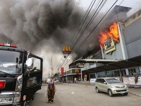 A firefighter stands in front of a burning shopping mall in Davao City on December 23, 2017 on the southern Philippine island of Mindanao.