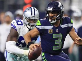 Russell Wilson of the Seahawks runs away from DeMarcus Lawrence of the Cowboys in the second half at AT&T Stadium on December 24, 2017 in Arlington, Texas. (Photo by Ronald Martinez/Getty Images) ORG XMIT: 700070833