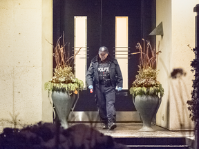 A Toronto police officer leaves the home of Honey and Barry Sherman who were found dead there, Friday Dec. 15, 2017.