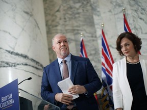 B.C. Premier John Horgan is joined by Minister of Energy Michelle Mungall after giving the green light for continuing construction on the controversial Site C Dam project during a news conference in Victoria on Monday.