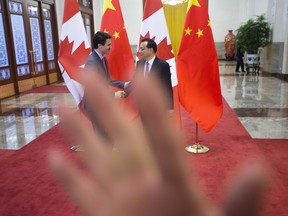 A security guard attempts to block a photo of Prime Minister Justin Trudeau being greeted by Chinese Premier Li Keqiang at the Great Hall of the People in Beijing, China on Monday, Dec. 4, 2017. ORG XMIT: SKP126
