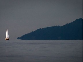 FILE PHOTO - A sailboat sails through a patch of sunlight on Burrard Inlet in Vancouver, as the southern tip of Bowen Island is seen in the distance on Wednesday December 25, 2013.