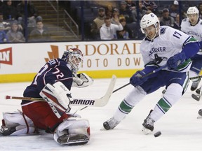 Columbus Blue Jackets' Sergei Bobrovsky, left, of Russia, makes a save against Vancouver Canucks' Nic Dowd during the third period of an NHL hockey game Friday, Jan. 12, 2018, in Columbus, Ohio.