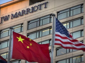 Chinese and American flags fly outside of a JW Marriott hotel in Beijing, Thursday, Jan. 11, 2018. The Marriot hotel chain apologized Thursday to China's government for referring to Tibet and self-ruled Taiwan as countries in a customer survey that news reports said Chinese police investigated as a possible crime.