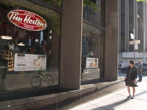 A woman walks pass a Tim Hortons in Toronto on Wednesday Aug. 2, 2017. The parent company of Tim Hortons says restaurants in select markets have increased prices on certain breakfast items.THE CANADIAN PRESS/Doug Ives