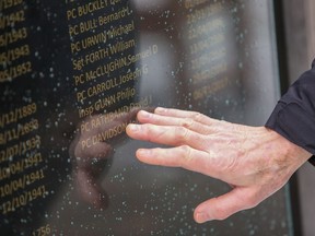 A person touches the name of Const. John Davidson on a police memorial at the Middle Engine Lane Police Station in Wallsend, U.K., in an undated police handout photo. Davidson's name has been added to a memorial for fallen officers in the U.K., after he was killed in November 2017 responding to reports of a stolen vehicle.