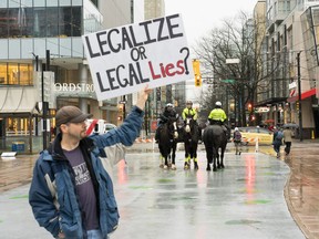 January 23, 2018 - Police watch on as a protestor waves a placard Tuesday afternoon outside the Vancouver Cannabis Farmers Market on Robson Street. Photo by Nick Eagland for Postmedia News.  [PNG Merlin Archive]