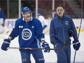 Sven Baertschi skates with coach Travis Green in practice, wearing the full face shield to protect his broken jaw.