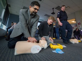 Neil Singh and David Willms work on a CPR practice dummy at the B.C. Emergency Health services building in Vancouver on Wednesday. A new app alerts trained bystanders when someone nearby suffers cardiac arrest, so they can begin CPR while waiting for paramedics to arrive.