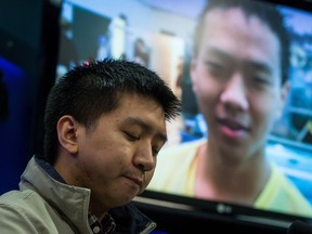Wilfred Wong pauses while speaking about his brother Alfred Wong, 15, seen on a television, who was an innocent victim of an alleged gang shooting, during a Vancouver Police news conference in Vancouver, B.C., on Monday January 22, 2018. Wong was hit by a stray bullet as his family was driving in Vancouver on January 13.