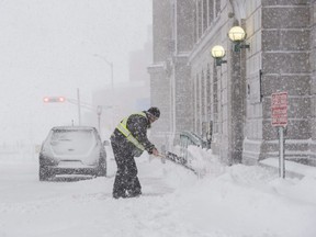 Josh Douthwright shovels snow at the entrance to the Federal Building on Highfield Street in downtown Moncton, N.B., on Thursday, January 4, 2018.