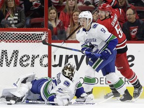 Jeff Skinner of the Carolina Hurricanes, right, watches a puck beat Vancouver Canucks' goaltender Jacob Markstrom while being checked by Canucks' defenceman Troy Stecher during Friday's NHL action in Raleigh, N.C.